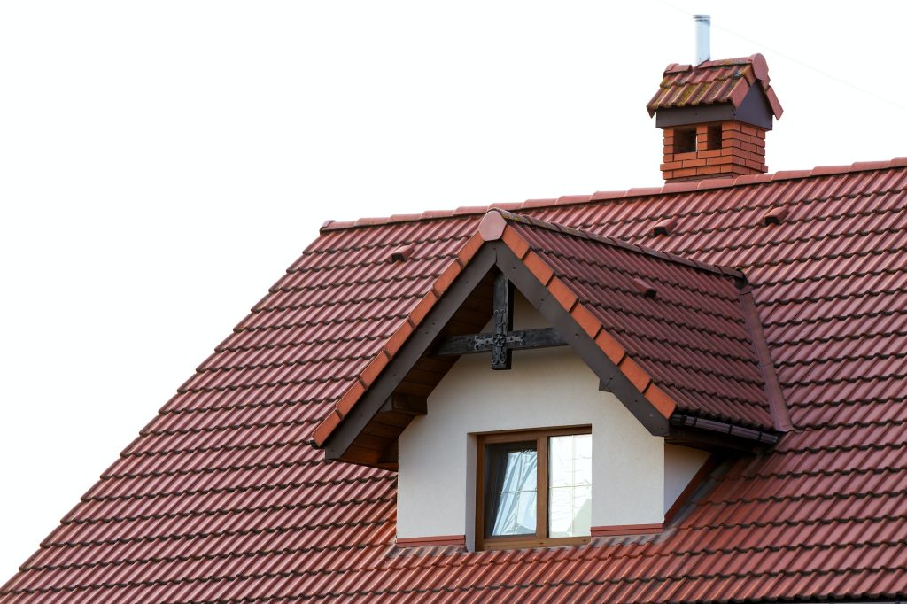 Close up of new orange roof with chimney and small modern window. Concept of modern roof with
